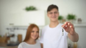 Young happy couple holding new house keys. Close up of couple hands holding key from new home on living room kitchen. housewarming people  in new apartment, Real estate moving home or renting property