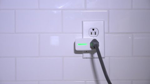 A close up shot of a man installing a smart plug into an ordinary kitchen outlet. Smarthome power electrical concept.  	