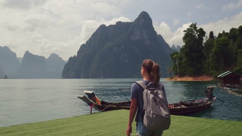 Young woman backpacker enjoy landscape view of mountain with long traditional thai boat, Asia, Thailand.