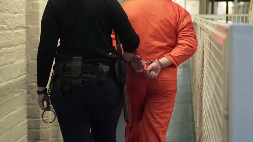 Prisoner In Shackles And Handcuffs Walking With Prison Guard, 4K Incarceration. Royalty-Free Stock Footage #1007909959