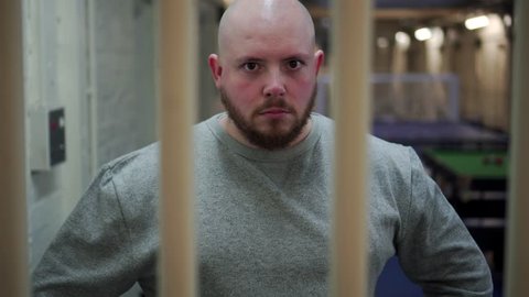 Portrait Of Angry Prisoner White Caucasian, Behind Prison Bars, 4K Incarceration.