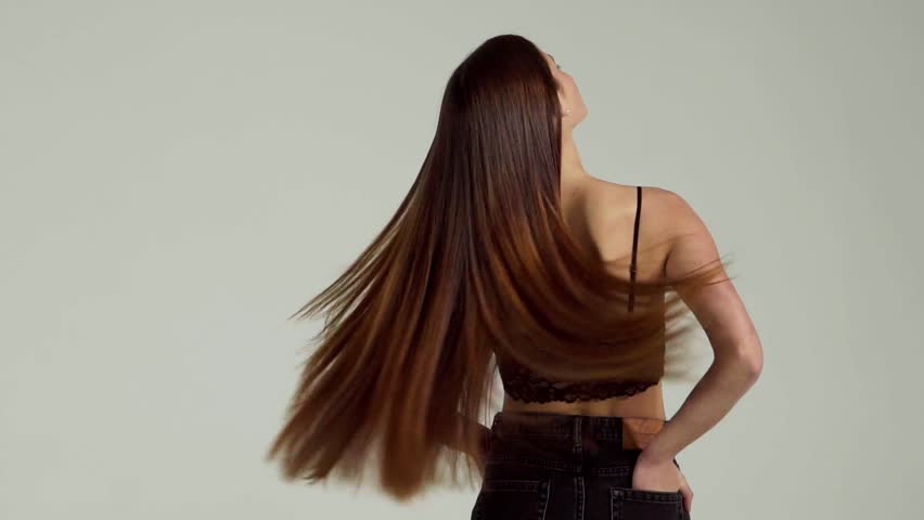 A girl with long dark and straight hair waves in a slow motion | Shutterstock HD Video #1007921767