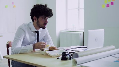 Young man having lunch in an office.
