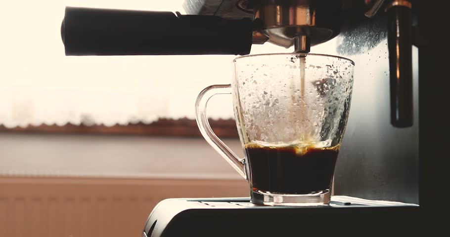 coffee machine or coffeemaker pouring espresso coffee at home in a glass cup