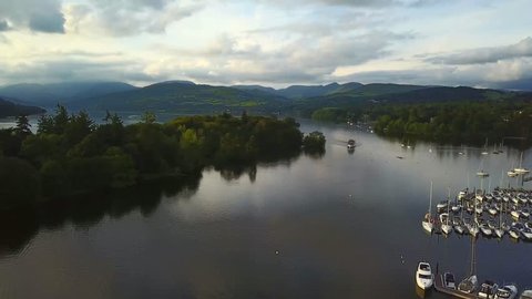 Aerial video of boat cruising along lake Windermere at sunset 