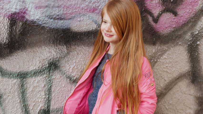 Little redheaded girl by graffiti wall