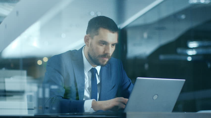 In the Office Businessman Sitting at the Desk Using Laptop Finishes Project and Wins Big. Makes Successful Gestures Raises Arms in Celebration. Shot on RED EPIC-W 8K Helium Cinema Camera. Royalty-Free Stock Footage #1007931994