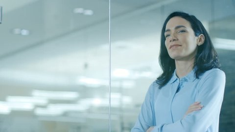 Beautiful Female CEO in Her Office Looks out of the Window. Strong Independent Woman with Big Accomplishments Behind and Ahead of Her. Shot on RED EPIC-W 8K Helium Cinema Camera.