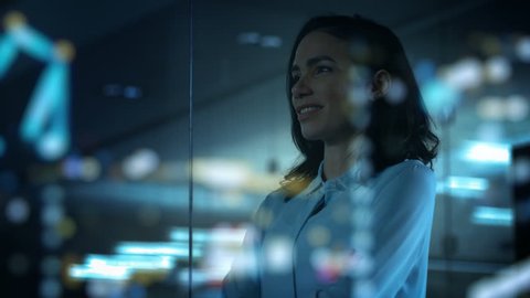 Beautiful Female CEO in Her Office Looks out of the Window on a Big City at Night. Strong Independent Woman with Big Accomplishments Behind and Ahead of Her. Shot on RED EPIC-W 8K Helium Cinema Camera