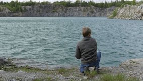 teen boy throwing stones into the water of the lake. Childhood dreams and memories. Ecology and environment, fresh air, clean water, radioactivity