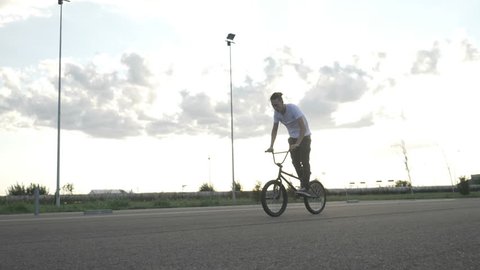 Slow motion of young biker pedaling and jumping practicing mid air moves with bike outside in the street