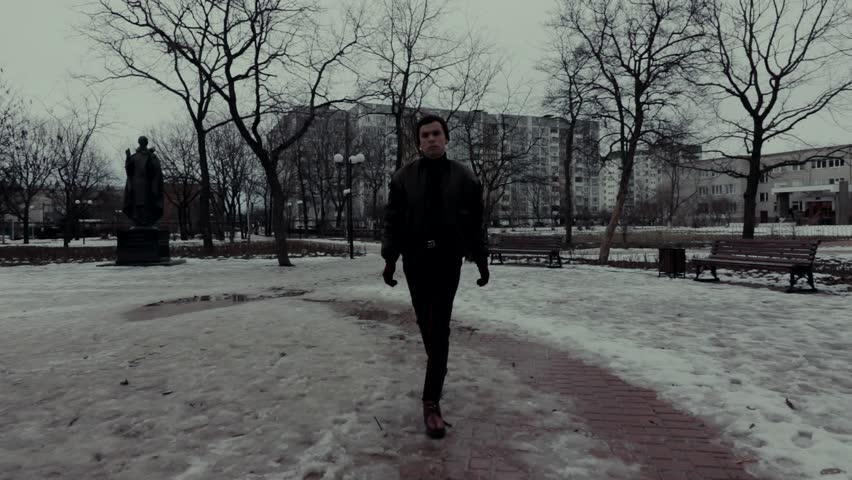 A young guy walks in the park, in winter in cloudy weather