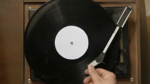 Top shot of male hand turning the vinyl record player on. Young man relaxing while listening to a retro style music alone at home.