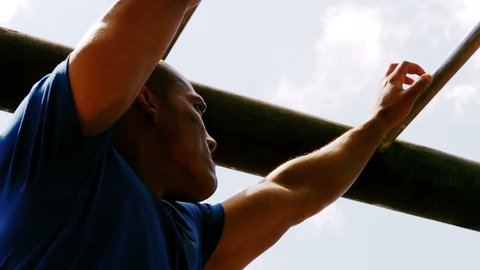 Man crossing the monkey bars during obstacle course in boot camp