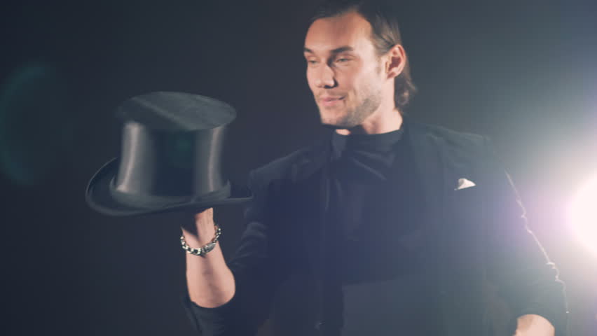 A man is twisting his top hat on a finger and smiling