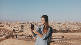 Cute tourist girl talks on video call. Jerusalem Israel. Pretty European traveler woman smiling happy and excited. 4K.