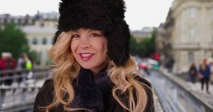 Tourist woman on old streets of Paris, France smiling at camera. Happy woman wears cozy hat and scarf while exploring urban streets in Paris. 4k
