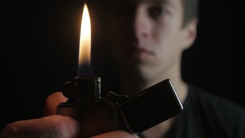 Close up Man opening and the burning of iron Zippo lighter on a black background