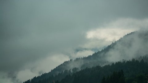 Timelapse - Rain clouds among forested mountains in Austrian Alps