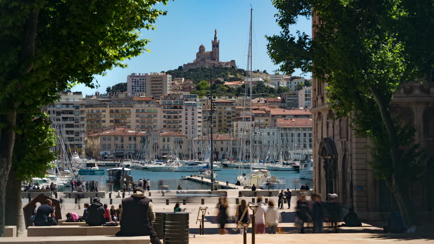 Timelapse - Crowds on city steps at the old port looking over to Basilica de Notre Dame de la Garde in summer