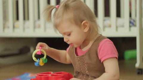 Little girl is playing with plastic toys at home or in kindergarten, baby child intellectual games of children