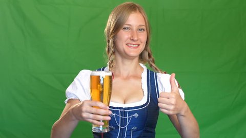 Woman in bavarian costume laughs and shows thumbs up. Green screen