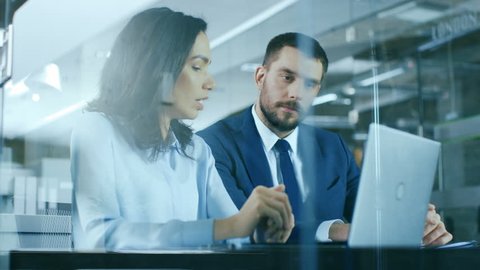 Female Accountant and Male Businessman Sitting at the Desk Having Discussion and Working on a Desktop Computer, Solving Problems. Modern Stylish Office with Beautiful People. Shot on RED EPIC-W 8K.
