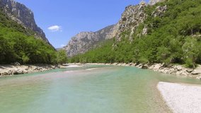 The two tall strong young mans and two beautiful girls is on the stony coast on the river Verdon, catamaran on parking, France, Provence, trees on background, photo shoot with a drone, remote control