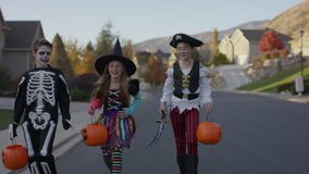 Front view tracking shot of children walking in neighborhood on Halloween / Cedar Hills, Utah, United States