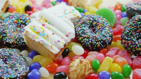 Overhead panning shot of junk food consisting of cakes, donuts, candy and sweets