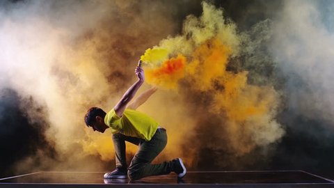 4K Men is dancing a new style solo dance with color smoke grenade in his hand. Slow motion Red Dragon camera (150fps) On Dark Black Background (high quality)