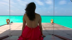 Girl in a Swinging Set Looking at the Ocean in Maldives Tropical Scenery with Blue Turqoise Waters in Slow Motion.