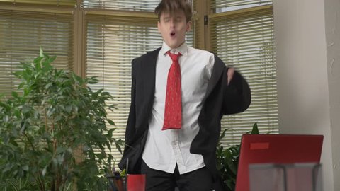 Young man in a suit dances in the office, makes funny faces, fools around, rejoices. Work in the office concept 60 fps
