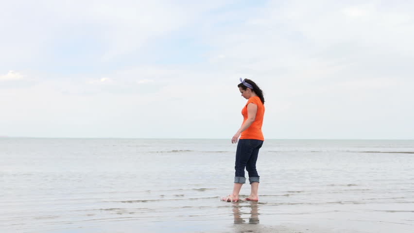 Girl walking through shore water in sandals