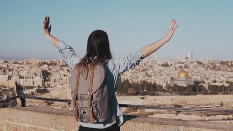 Excited European tourist girl raises hands happy. Israel, Jerusalem. Woman with arms wide open. Freedom. Slow motion.