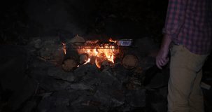 Man standing watching a burning BBQ fire