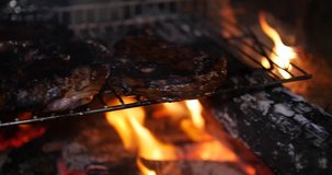 Panning clip of meat grilling over a hot fire
