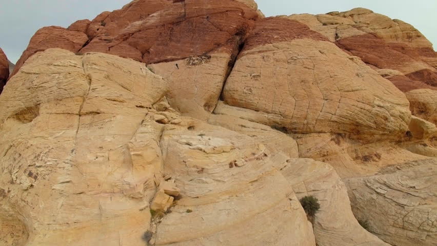 Drone shot flying towards rock climbers scaling a rock formation in Joshua Tree National Park