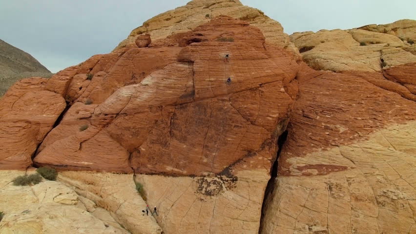 Cinematic drone shot rising up and tilting down to focus on rock climbers in Joshua Tree National Park