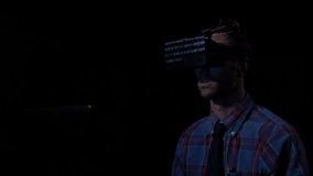 Futuristic computer programmer worker sitting in a dark room and trying VR glasses at home to check sequential binary code for his website