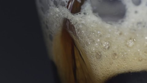 A slow motion shot of beer dark stout poured into a glass