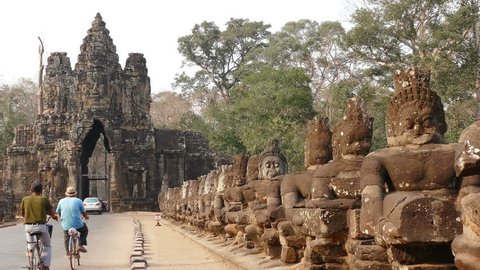 Group of cyclists on the background of the main gate of ancient Angkor Wat temple in Cambodia.
