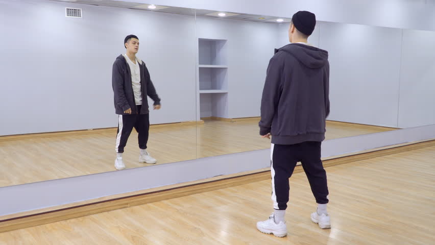 Young handsome guy dances in front of the mirror