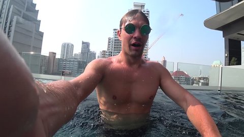A young white handsome male doing an underwater selfie on an action camera. Portrait of a young man with glasses taking himself off to the camera under water. 4k