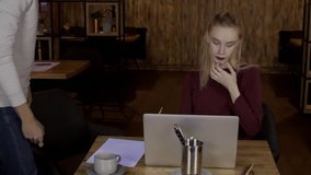 For laptop sits couple and man is surprised looking at monitor of woman. Man's person experiences emotions from promotion of online stores on computer for which female blonde buys. slow motion video