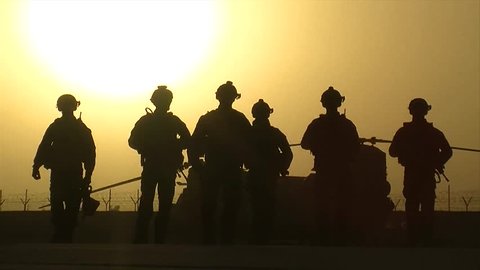 Afghanistan - February 26, 2008: Slow motion of silhouette of soldiers walking at a base in Afghanistan at sunset