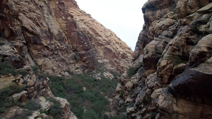 Slow drone shot flying backwards through a narrow canyon trail in Joshua Tree National Park