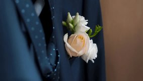 Boutonniere in the pocket of the jacket of the groom in his wedding day. Clip. Rose in his jacket pocket