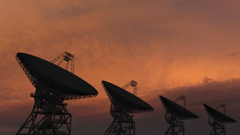 Satellite dishes moving in time-lapse against a sunset sky.