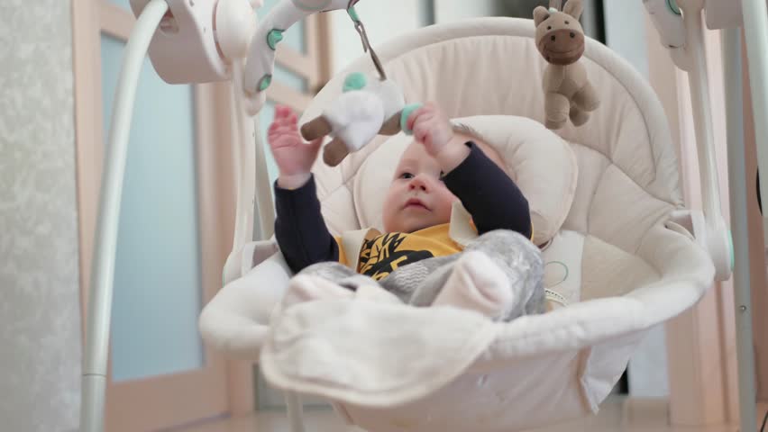 Newborn baby boy swinging on electric swing and playing toys Royalty-Free Stock Footage #1008049027